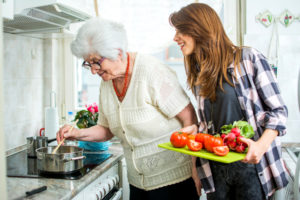 Grandmother and her granddaughter cooking together in kitchen.